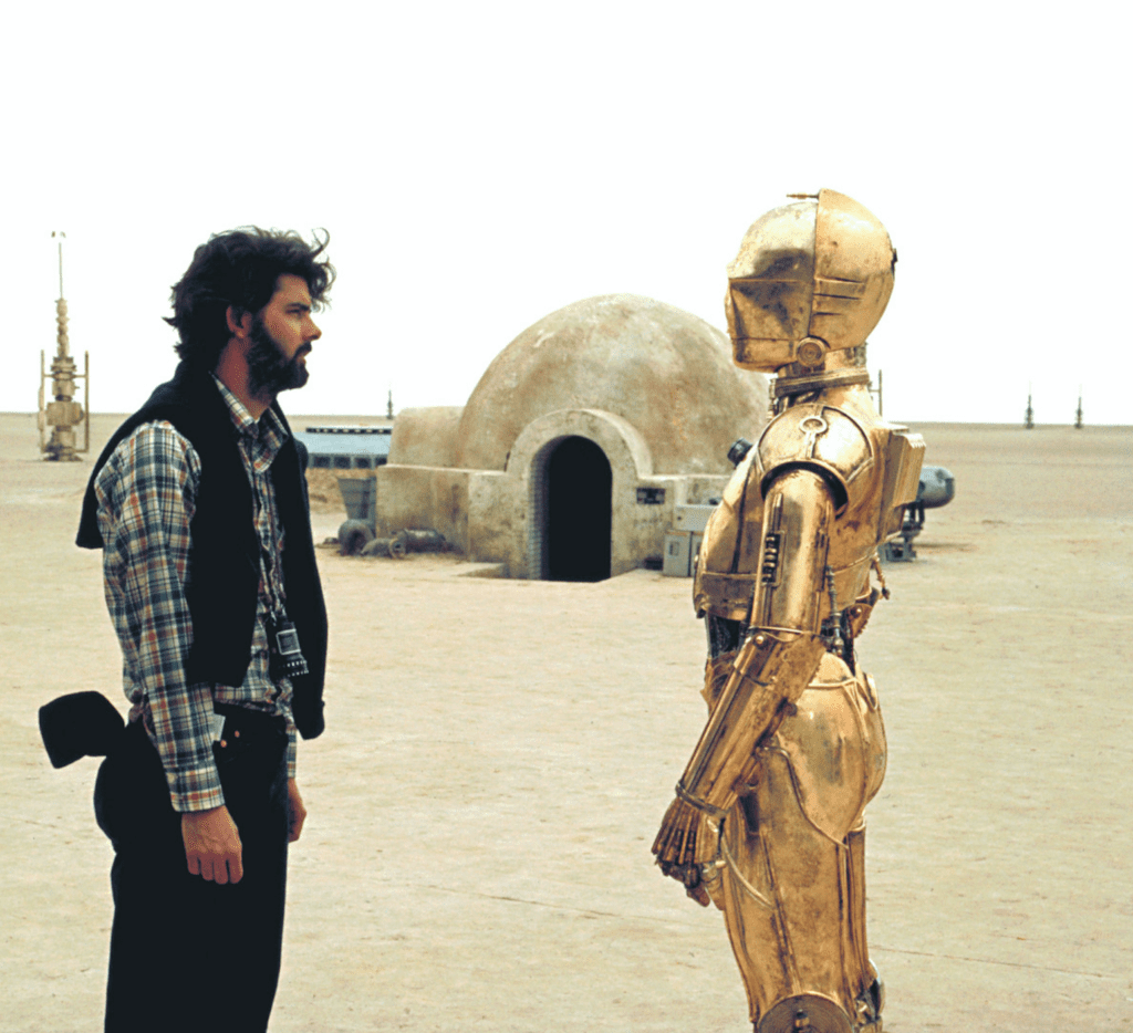 George Lucas with Anthony Daniels as C-3PO on the Star Wars Set [Source: Biography/Getty]